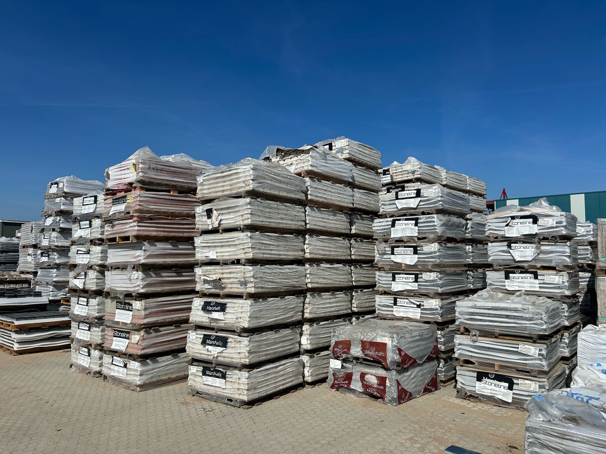 Partijen tegels op pallets bij DB Trading, waaronder de merken Stoneline en Marshalls